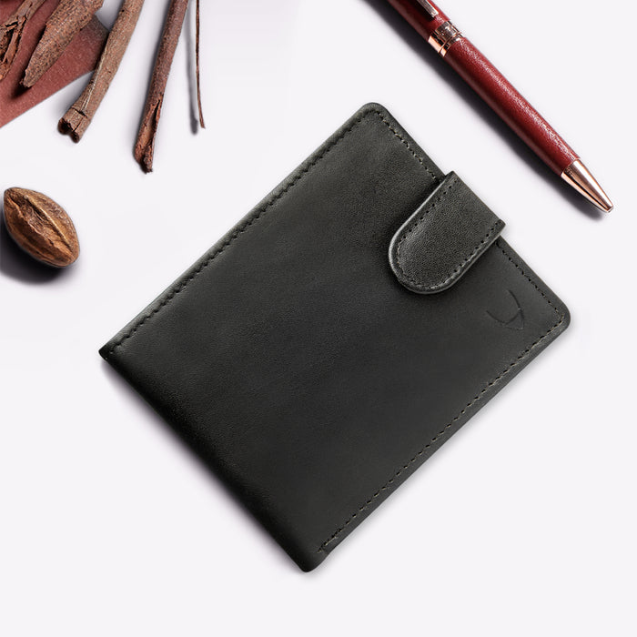 A black Hidesign leather wallet with a snap closure, styled with pen and spices on a clean backdrop.